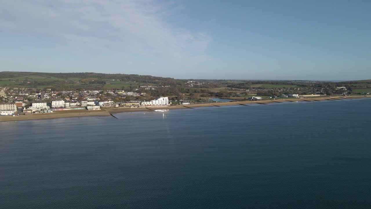 Aerial view of Sandown a seaside resort and civil parish on the south-east coast of the Isle of Wight, England. Drone rotating to the right over the sea showing the beach and the buildings