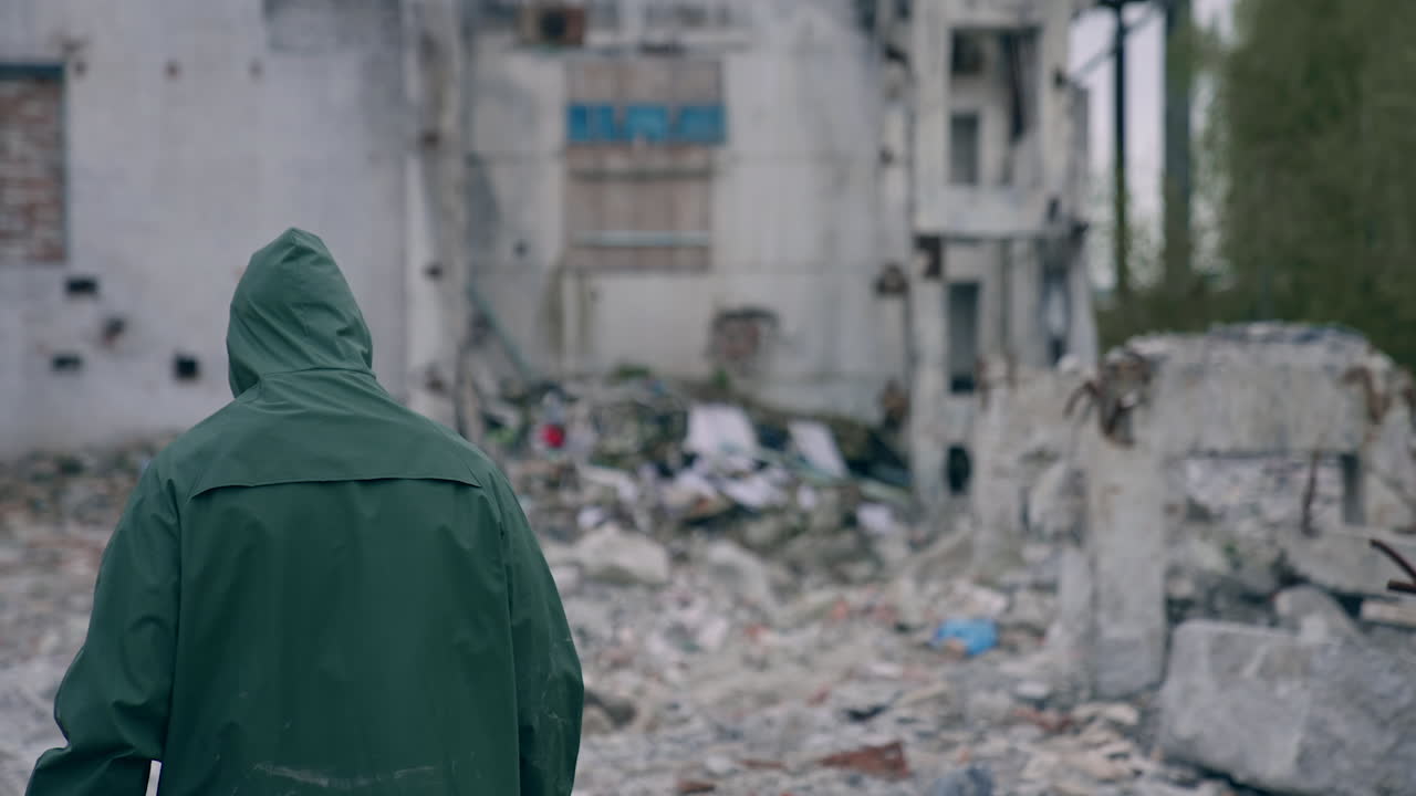 Stalker survivor after nuclear chemical war. Man in protective uniform and gas mask in destroyed place. Man-made disaster. Post apocalyptic world. Back view.