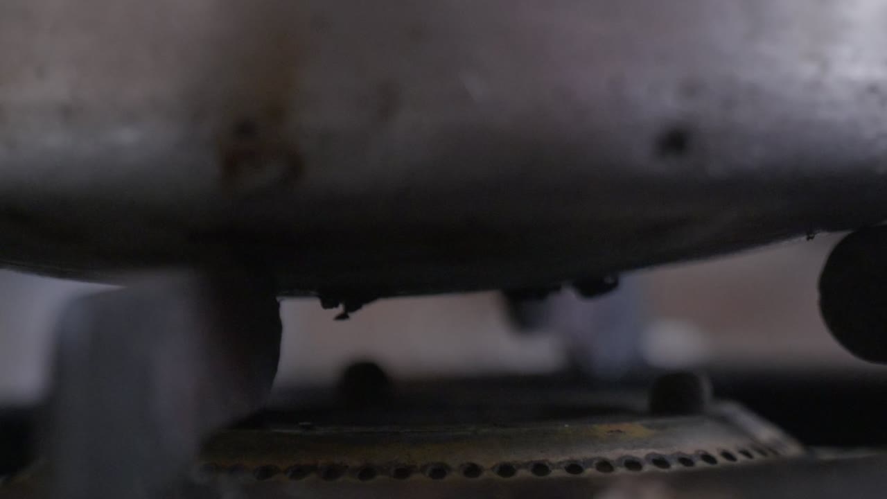 Igniting a Gas Stove with a Lighter Under aluminum bowl with red to blue flame. internal shot, close-up shot, 4k