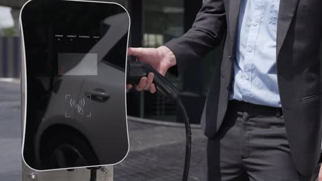 progressive businessman plugs charger plug from charging station to his ev.