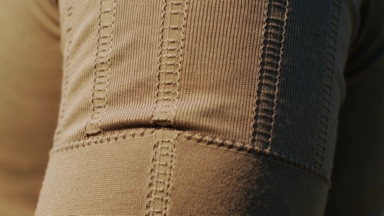 Camera panning, revealing beige ribbed knit sleeve in studio, showing texture and seam fold