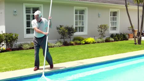 hombre mayor limpiando la piscina con una red