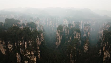 wide aerial view of forest-covered sandstone pillars stretching across a misty valley in the vast terrain of zhangjiajie national park