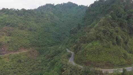 aerial view of winding mountain road through lush green mountains