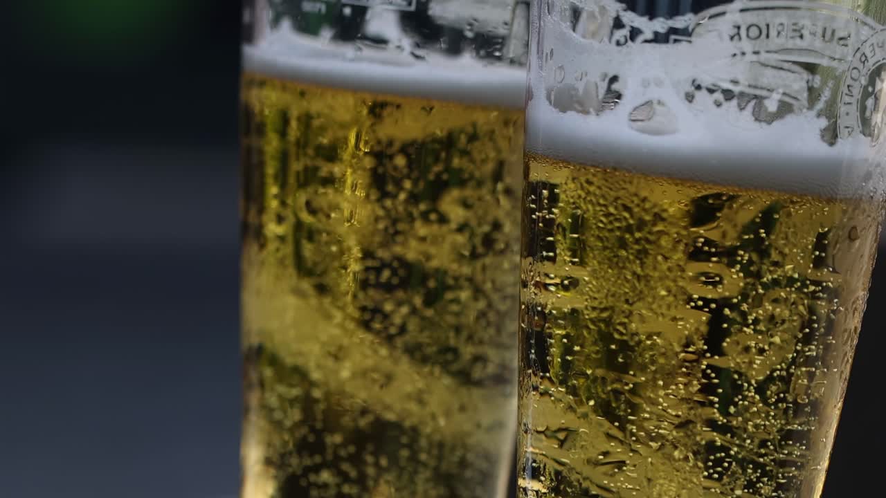 Detailed view of two beer glasses with effervescent bubbles and frothy tops.