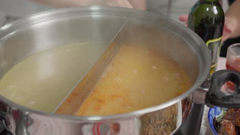 close-view-of-Boiling-tomyum-soup-and-collagen-soup-bubbling-in-separate-pots