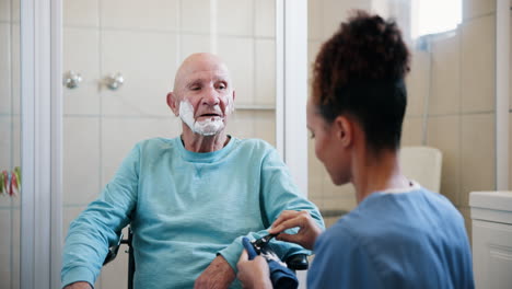 elderly man receiving shaving assistance