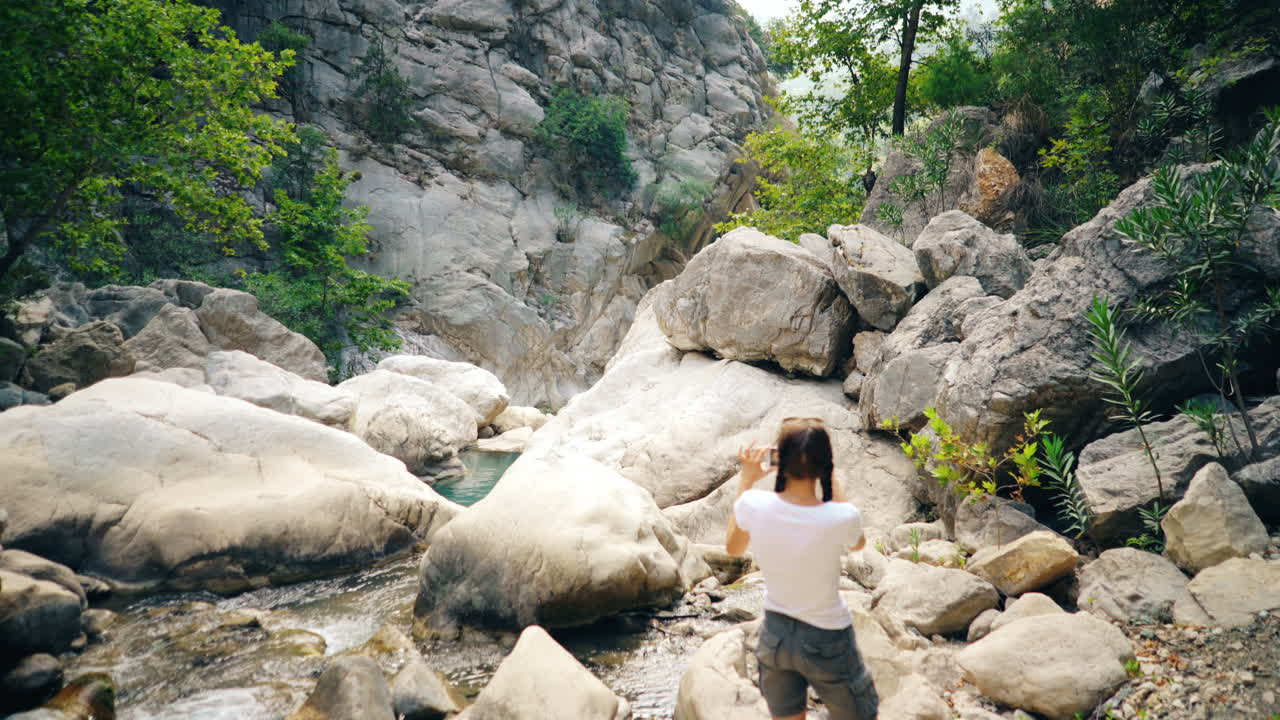 Woman taking pictures of a beautiful canyon with a river
