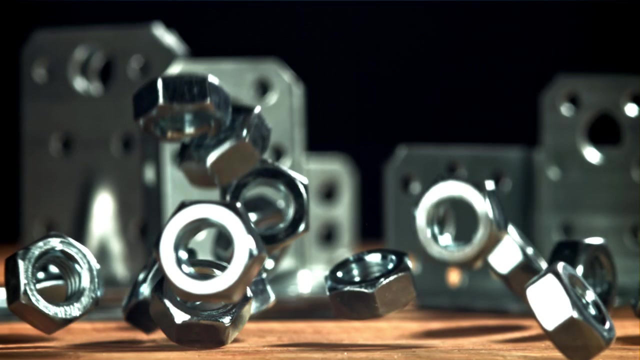Shiny Metal Nuts Falling and Bouncing on a Wooden Surface