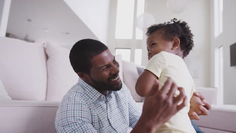 father playing with baby daughter lifting her in the air at home