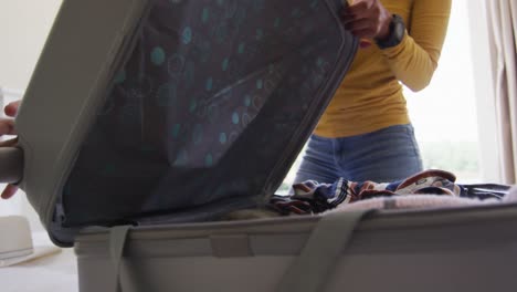 sección media de una pareja biracial aplaudiendo con alegría después de empacar la maleta para el viaje