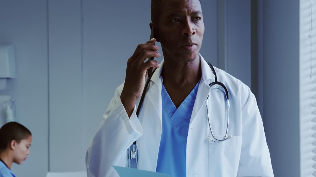 Front view of African American male doctor talking on mobile phone in hospital 4k