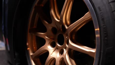 Detail-shot-of-the-front-golden-wheel-with-low-profile-tires-of-a-sports-car-at-night