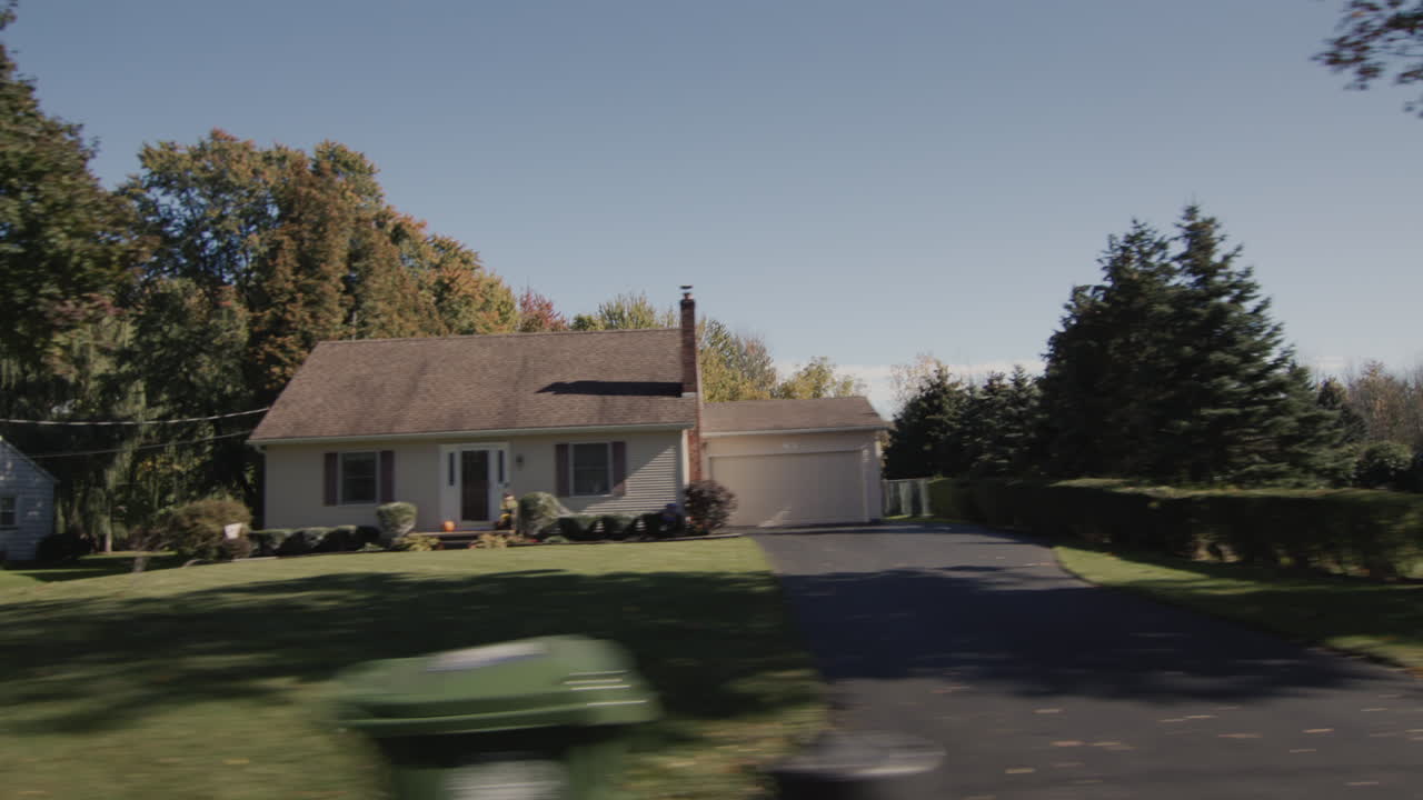 Kørsel langs en typisk gade i en amerikansk by på en klar efterårsdag. Set fra siden.