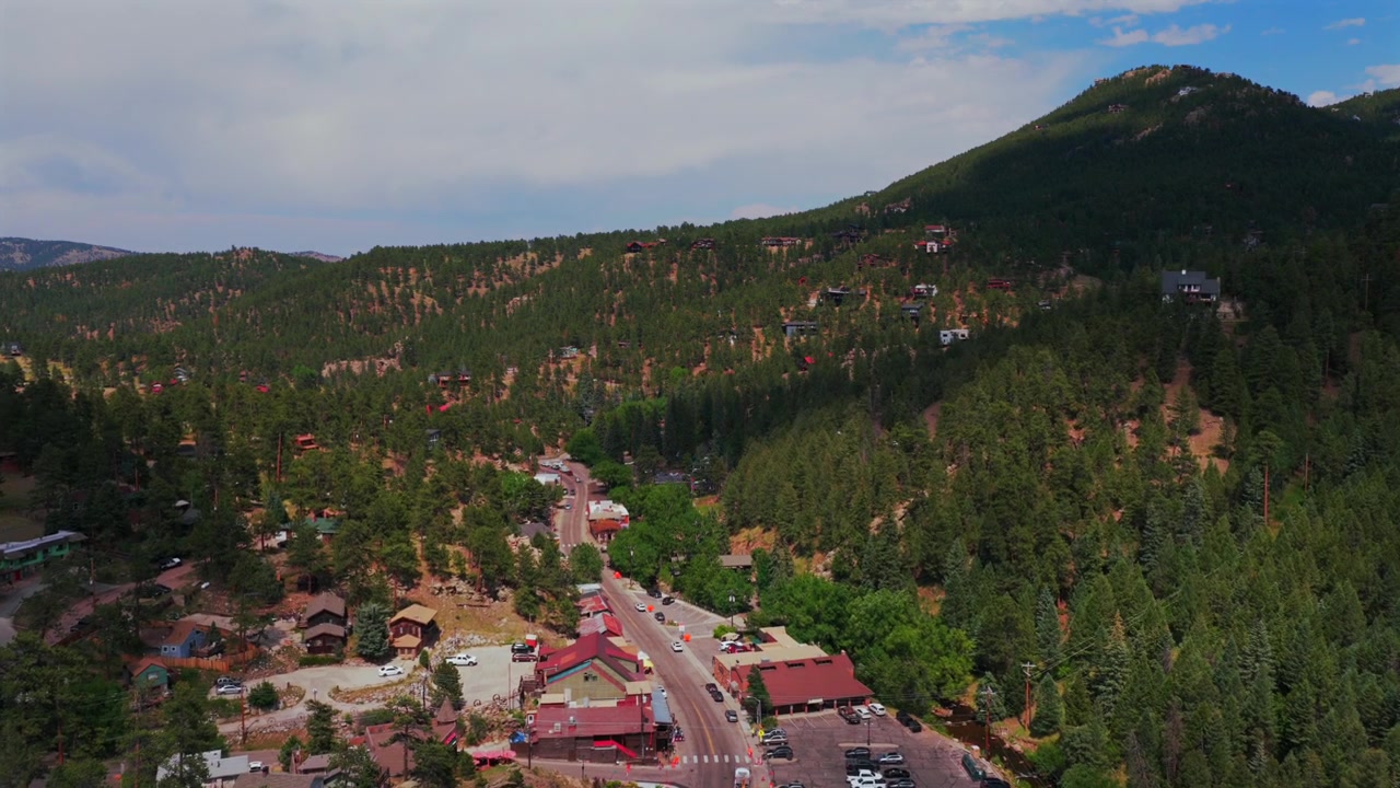 Centro de Evergreen Colorado, rua principal, edifícios comerciais, carros, vista aérea de drone, Front Range, Montanha Bear, Montanhas Rochosas, pequena cidade, verão, primavera, manhã ensolarada e nublada, movimento para frente.