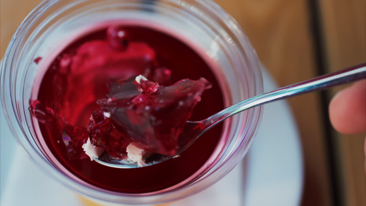Close up of a spoon breaking into vibrant red jelly dessert