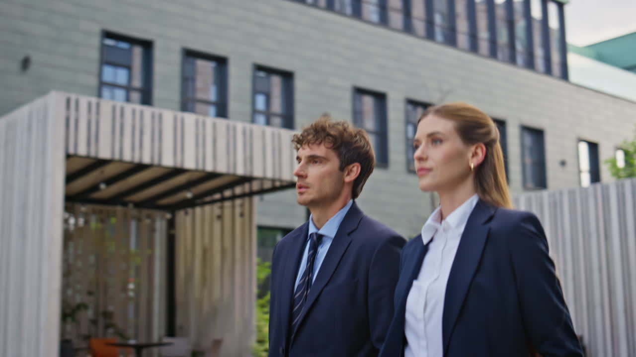 Confident businessman businesswoman walking together on urban street closeup