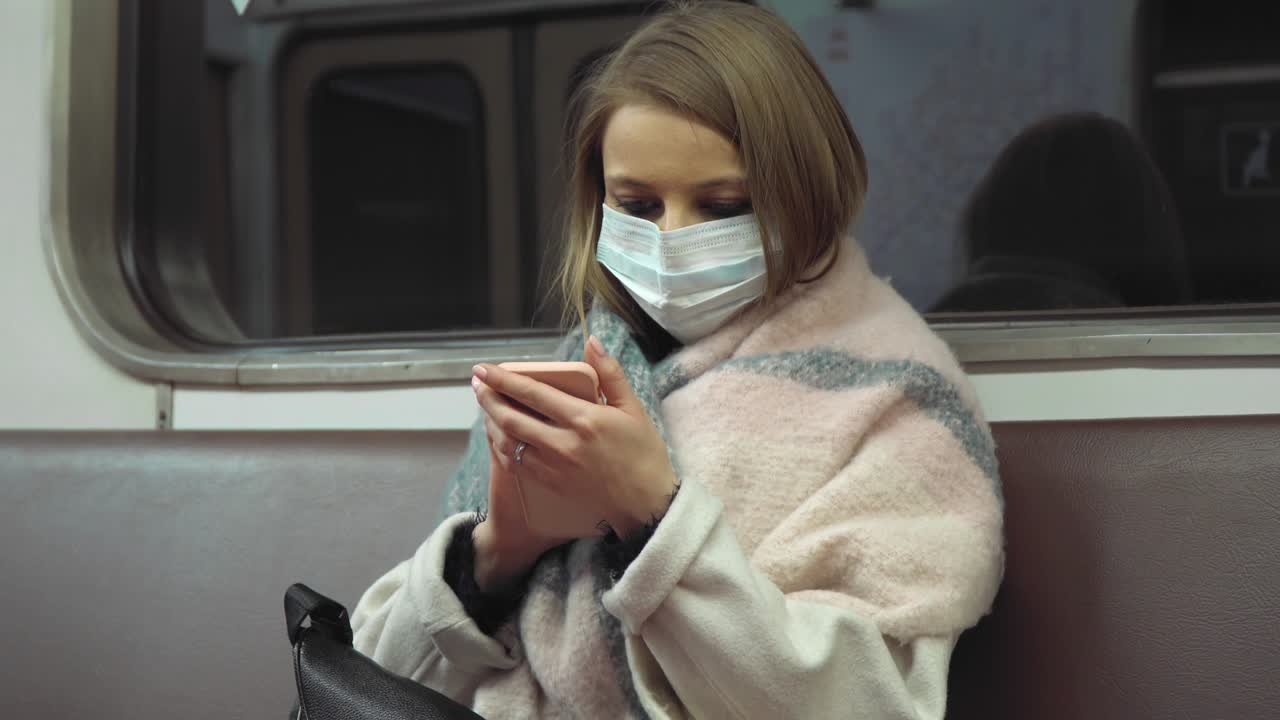 chica con una máscara médica sentada en un vagón del metro y la pantalla de desplazamiento