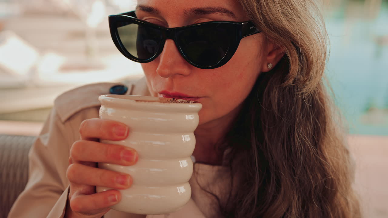 Woman holding a cup of hot chocolate, with cocoa powder visible on top
