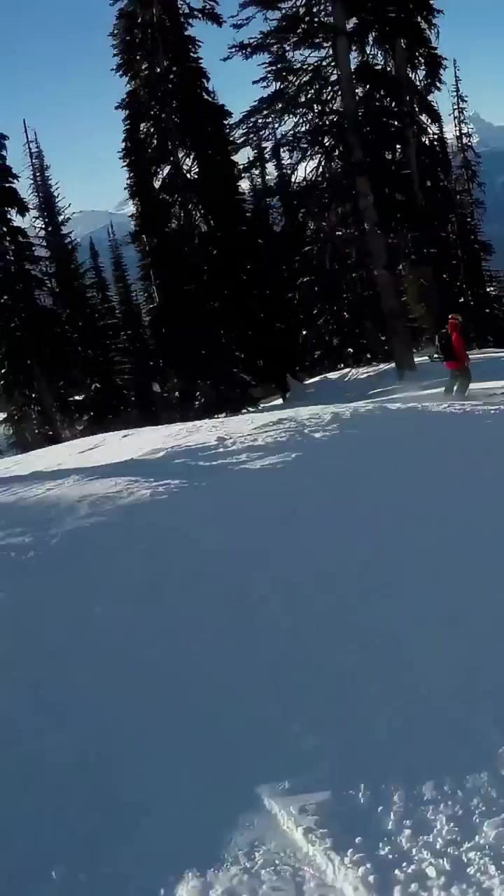 Vertical video: Pushing off from pause skier in helmet skiing on red skis down run, avoiding skiers