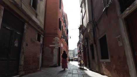 Vista-Trasera-De-Una-Mujer-Caminando-Por-Viejos-Callejones-En-Venecia,-Italia