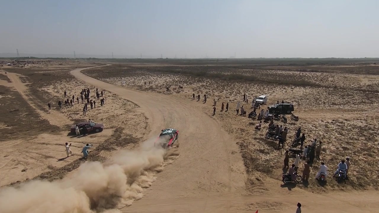 Vista aerea di una Jeep da rally che solleva polvere mentre guida in curva all'Hub Rally Cross 2023, slow motion, ripresa in movimento