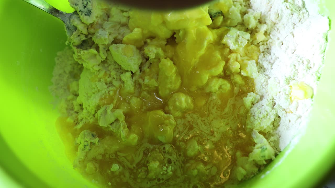 빵 굽는 사람은 구타 계란을 밀가루에 넣습니다 - 빵 반죽 준비 - 높은 각도, 클로즈업