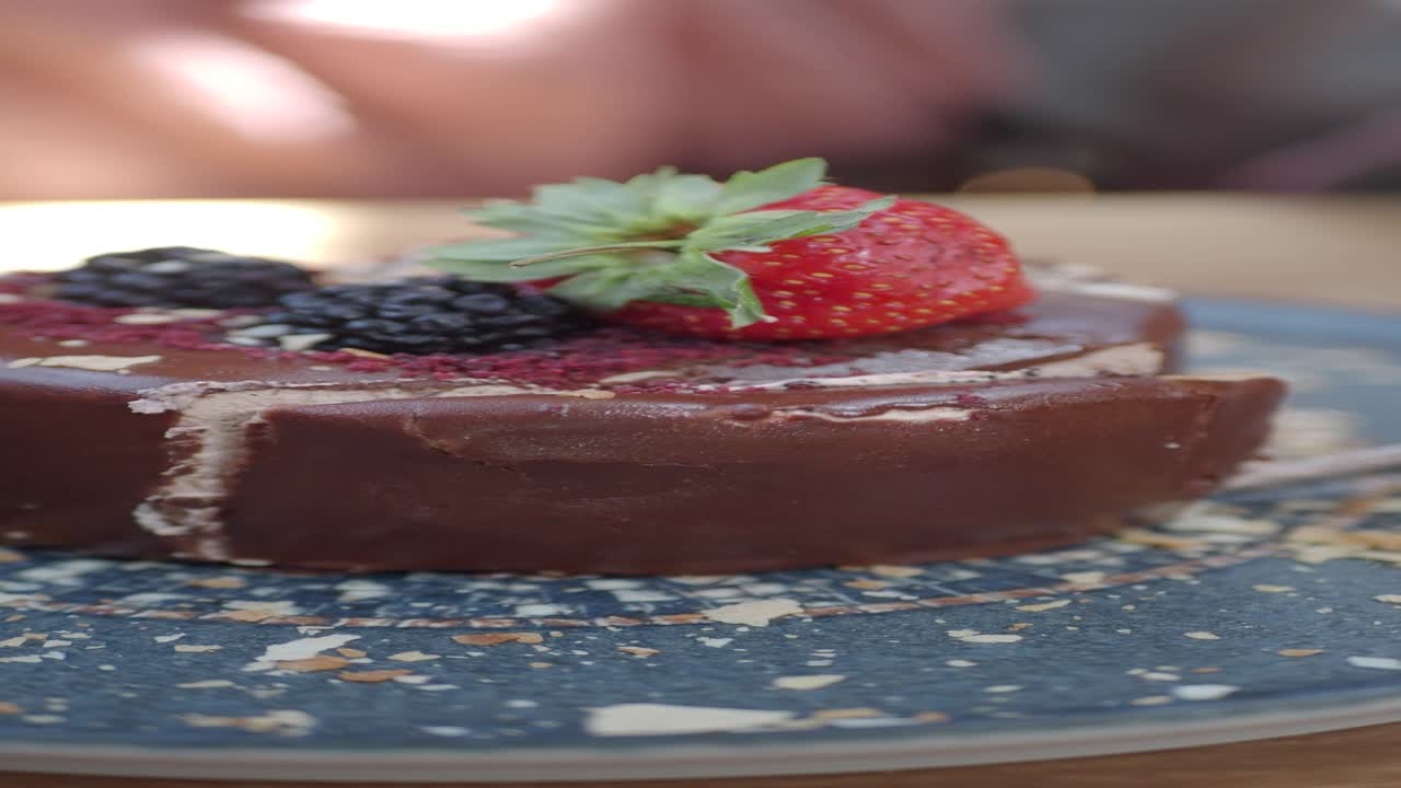 cerca de un pastel de chocolate con una fresa y moras en la parte superior