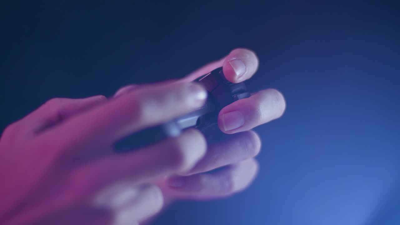 Playing video games on a small controller using triggers playing quickly with blue lens flare black background