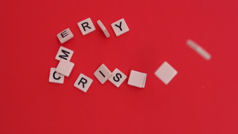 letter tiles moving to spell merry christmas on red background