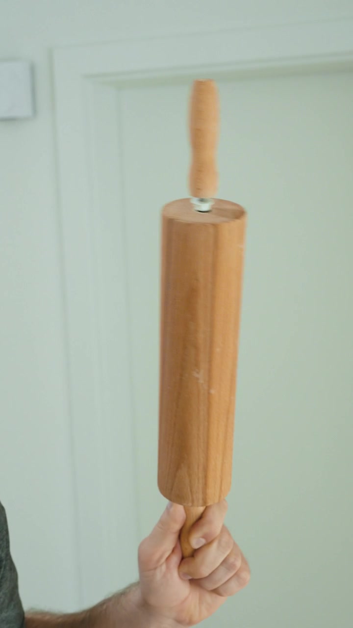 Primo piano di una persona che tiene utensili da cucina in legno, mostrando strumenti di cottura, materiali naturali, articoli per la casa, attrezzature da cucina e preparazione tradizionale del cibo.