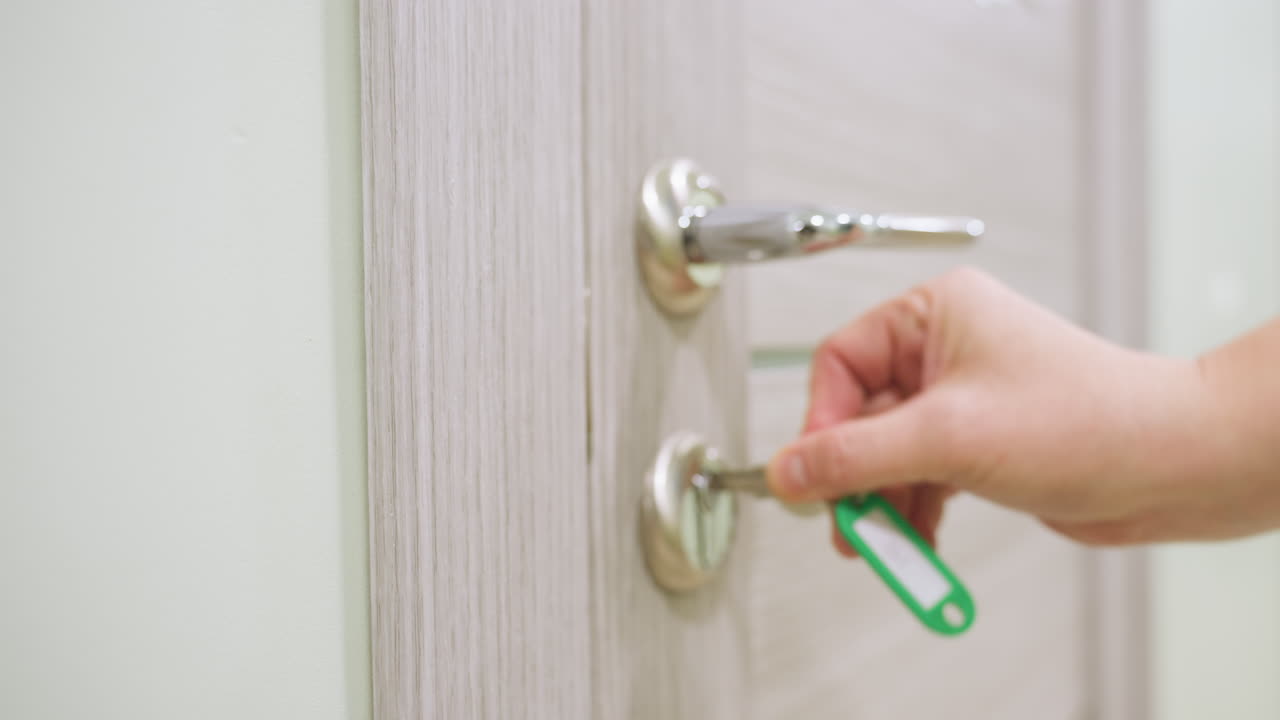 Female staff unlocks modern wooden door with chrome handle steps inside softly lit hallway and gently closes door behind her reflecting routine office access or residential entry in calm environment