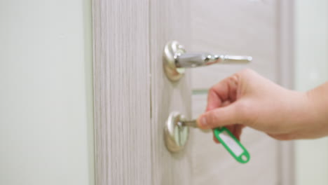 female staff unlocks modern wooden door with chrome handle steps inside softly lit hallway and gently closes door behind her reflecting routine office access or residential entry in calm environment