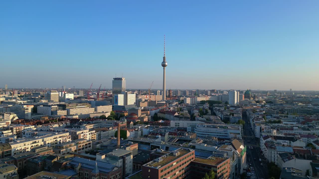 Berlin tv tower standing tall over the tower and red town hall, bathed in the warm glow of golden hour. Perfect aerial view flight ascending drone