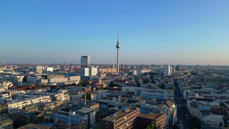 berlin tv tower standing tall over the tower and red town hall, bathed in the warm glow of golden hour. perfect aerial view flight ascending drone