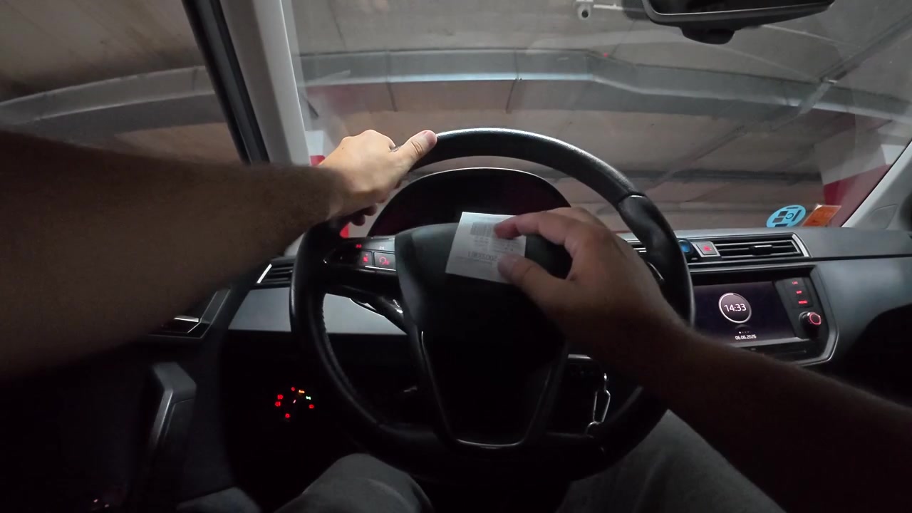 Driver Holding Parking Ticket Inside Car in Underground Garage