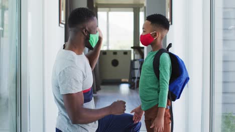 African-american-father-helping-his-son-with-putting-face-mask-on