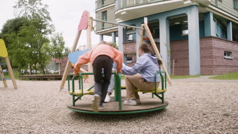 una niña con síndrome de down jugando con sus amigos en el parque en un día ventoso. están girando en un carrusel