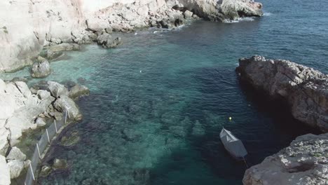 Vuelo-Aéreo-Lento-A-Lo-Largo-De-La-Grada-De-Un-Antiguo-Pueblo-De-Pescadores-En-Ghar-Lapsi-En-La-Provincia-Siggiewi-De-Malta,-Un-Popular-Destino-Turístico-Debido-A-Las-Aguas-Cristalinas