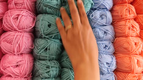 una mano seleccionando una bola de hilo de una variedad de colores
