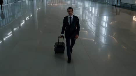 a man in a suit walks with luggage through a modern airport hall