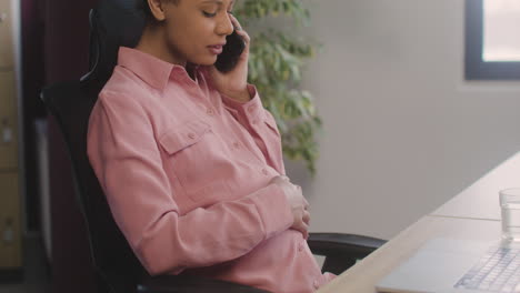 Pregnant-Woman-Talking-On-Her-Mobile-Phone-And-Caressing-Her-Belly-While-Working-In-The-Office-3