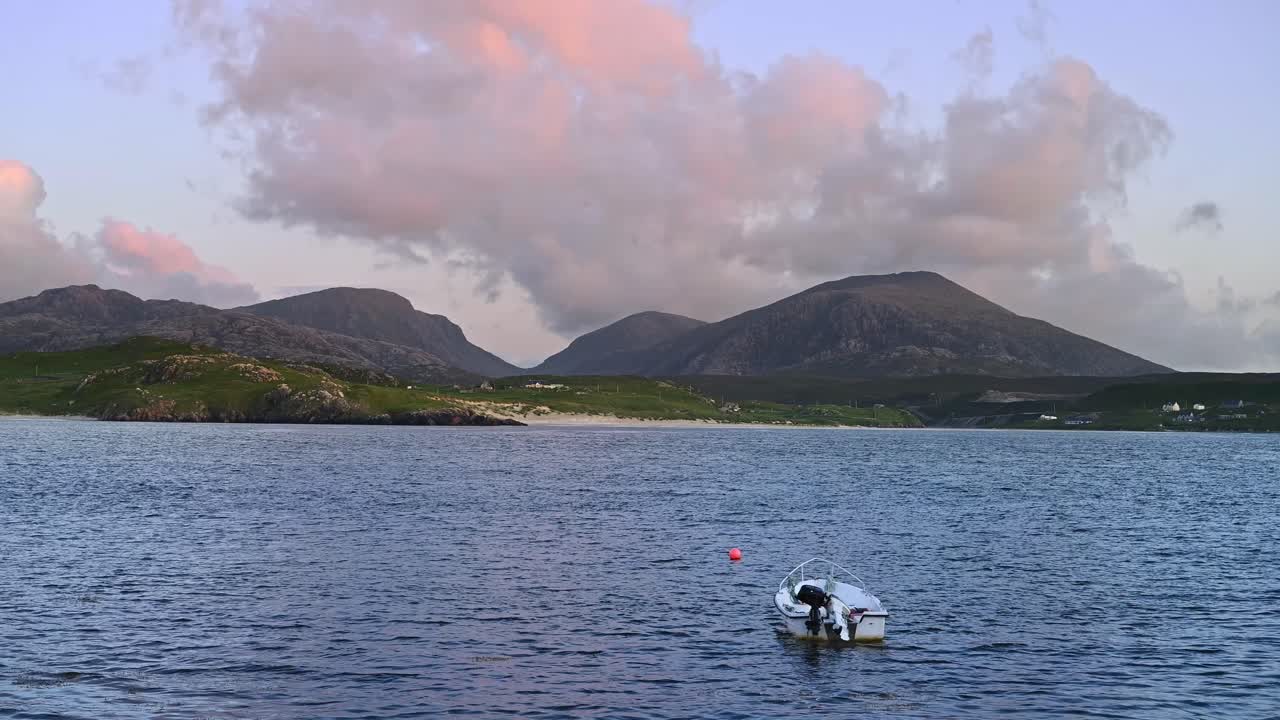 Pink sunset behind rocky hills and calm sea at Uig Bay, Isle of Lewis