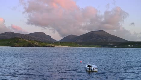 pink sunset behind rocky hills and calm sea at uig bay, isle of lewis