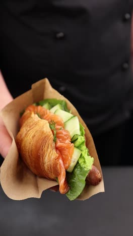 chef holding a delicious smoked salmon croissant sandwich