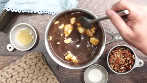 baking delicious caramel pecan brownies. in a sauce pan stirring and melting butter for a caramel topping. freshly baked gooey chocolate brownies with sweet caramel and nutty pecans.