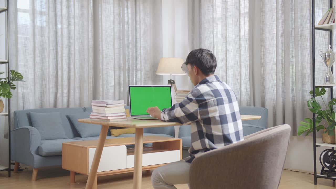 초록색 화면의 노트북으로 집에서 일하는 사람