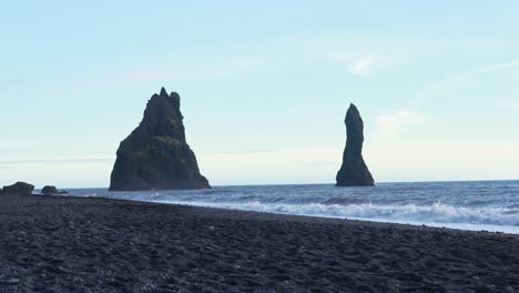 Reynisdrangar-Volcanic-Rock-Formations-Sticking-Out-Of-Ocean-In-Reynisfjara-Black-Sand-Beach-in-Iceland