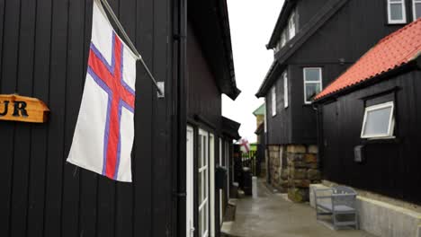 gentle breeze blowing on faroese flag on wooden exterior in gasadalur, vagar, faroe islands