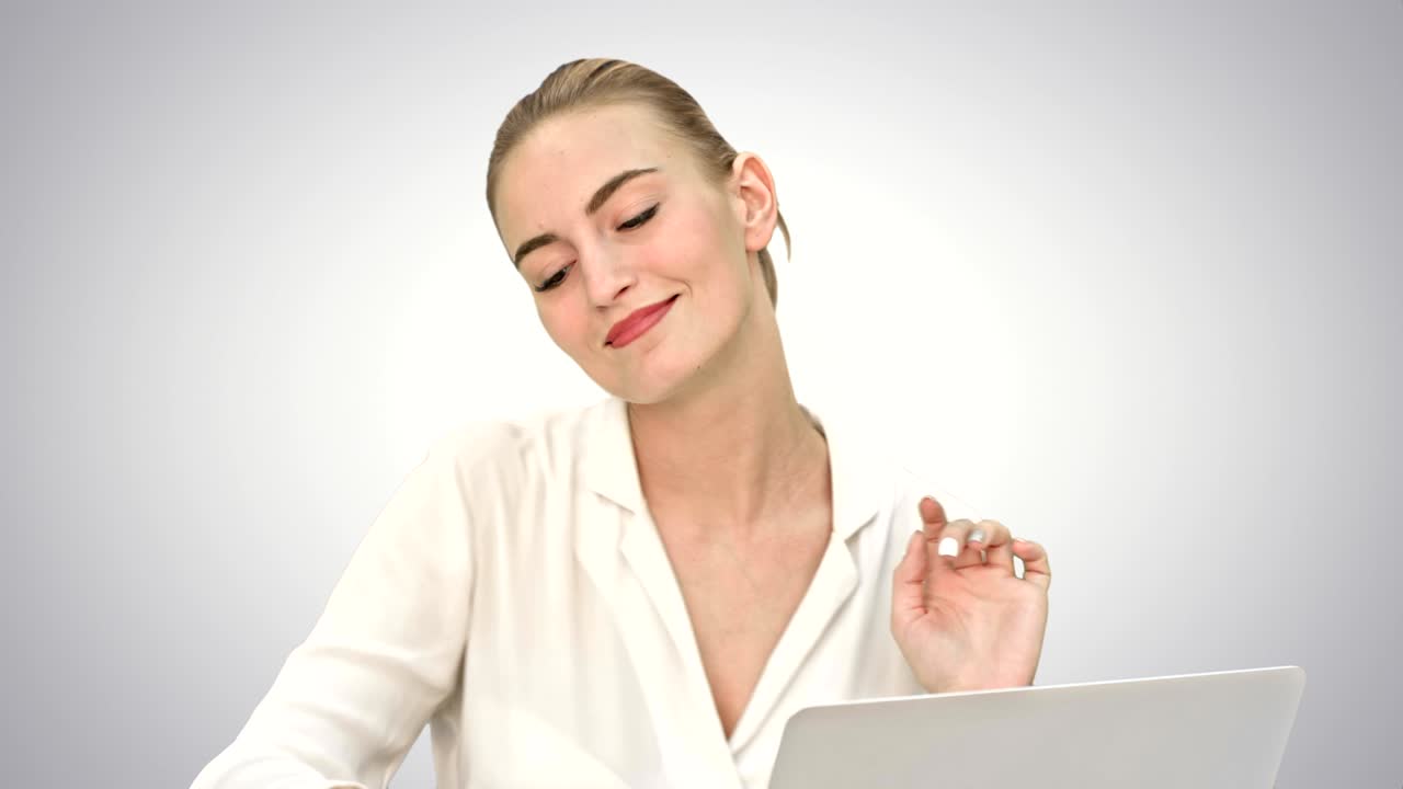 mujer de negocios en un buen estado de ánimo baile, sentado en el escritorio con una computadora portátil, y responder a una llamada telefónica en fondo blanco